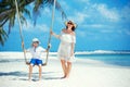 Young beautiful woman swinging son on a tropical beach, Koh Phangan island. Thailand. Royalty Free Stock Photo