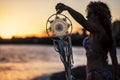 Young beautiful woman take a dreamcatcher during the wonderful sunset at the beach in front of the ocean. feeling with the nature