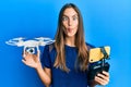 Young beautiful woman taking a selfie photo with smartphone flying drone making fish face with mouth and squinting eyes, crazy and