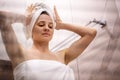 Young beautiful woman after taking a shower standing in the bathroom wipes her hair with a white towel Royalty Free Stock Photo