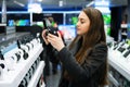 Beautiful woman testing headphones in modern store