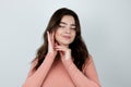 Young beautiful woman touches her face with both hands standing on isolated white background looking satisfied , pure beauty Royalty Free Stock Photo