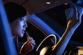 Young beautiful woman in traditional Chinese dress putting on lipstick in the rear view mirror of the car at night Royalty Free Stock Photo