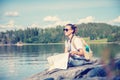 Young beautiful woman traveler with a map in hands sits on a lake in Norway