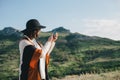 Young beautiful woman traveler wearing hat and poncho taking pictures on her smart phone Royalty Free Stock Photo