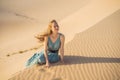 Young beautiful woman traveling in the desert. Sandy dunes and blue sky on sunny summer day. Travel, adventure, freedom Royalty Free Stock Photo