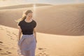 Young beautiful woman traveling in the desert. Sandy dunes and blue sky on sunny summer day. Travel, adventure, freedom Royalty Free Stock Photo