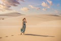 Young beautiful woman traveling in the desert. Sandy dunes and blue sky on sunny summer day. Travel, adventure, freedom Royalty Free Stock Photo