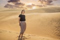 Young beautiful woman traveling in the desert. Sandy dunes and blue sky on sunny summer day. Travel, adventure, freedom Royalty Free Stock Photo