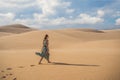 Young beautiful woman traveling in the desert. Sandy dunes and blue sky on sunny summer day. Travel, adventure, freedom Royalty Free Stock Photo