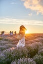 Young beautiful woman traveller with basket in a straw hat and long romantic dress standing in lavender field and Royalty Free Stock Photo