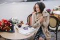 Young beautiful woman in trench coat drinking coffee in a street cafe