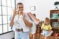 Young beautiful woman with two daughters holding shopping bags at retail shop doing ok sign with fingers, smiling friendly Royalty Free Stock Photo