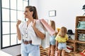 Young beautiful woman with two daughters holding shopping bags at retail shop pointing thumb up to the side smiling happy with Royalty Free Stock Photo