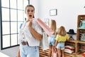 Young beautiful woman with two daughters holding shopping bags at retail shop scared and amazed with open mouth for surprise, Royalty Free Stock Photo