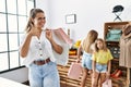 Young beautiful woman with two daughters holding shopping bags at retail shop smiling happy and positive, thumb up doing excellent Royalty Free Stock Photo