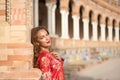 Young and beautiful woman in a typical Moroccan red costume, with embroidery with gold and silver threads, leaning on a brick