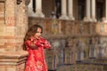 Young and beautiful woman in a typical Moroccan red costume, with embroidery with gold and silver threads, leaning on a brick