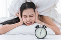 Young beautiful woman use the pillow to close the ears while the alarm clock in morning Royalty Free Stock Photo