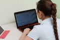 A young beautiful woman uses a laptop while sitting at her workplace, a cheerful smiling girl. Technology, business, homework, Royalty Free Stock Photo