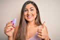 Young beautiful woman using beauty sponge with facial makeup over pink background happy with big smile doing ok sign, thumb up Royalty Free Stock Photo