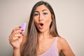 Young beautiful woman using beauty sponge with facial makeup over pink background scared in shock with a surprise face, afraid and Royalty Free Stock Photo