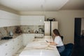 Young beautiful woman using cell phone and having a coffee in the kitchen. Royalty Free Stock Photo