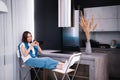 Young beautiful woman using cell phone while sitting in the kitchen after coming back home from work. Royalty Free Stock Photo