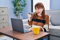 Young beautiful woman using computer laptop doing video call pointing thumb up to the side smiling happy with open mouth Royalty Free Stock Photo
