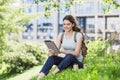 Young beautiful woman using digital tablet in a city park. Smiling girl resting outdoor. Royalty Free Stock Photo