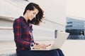 Young beautiful woman using laptop computer in the city street. Beautiful female hands working on laptop outdoor. Royalty Free Stock Photo