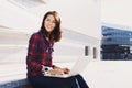 Young beautiful woman using laptop computer in the city street. Pretty happy girl working on laptop outdoor. Royalty Free Stock Photo