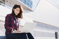 Young beautiful woman using laptop computer in the city street. Pretty happy girl working on laptop outdoor. Royalty Free Stock Photo