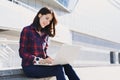 Young beautiful woman using laptop computer in the city street. Pretty happy girl working on laptop outdoor. Royalty Free Stock Photo