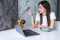 Young beautiful woman using laptop while having breakfast in modern kitchen Royalty Free Stock Photo