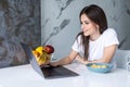 Young beautiful woman using laptop while having breakfast in modern kitchen Royalty Free Stock Photo