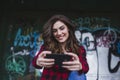 Young beautiful woman using mobile phone. She is taking a picture. Urban graffiti background. Outdoors lifestyle.Technology Royalty Free Stock Photo