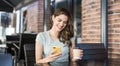 Young beautiful woman using smart phone in a cafe. Pretty student girl sitting in a coffee shop and typing on mobile phone Royalty Free Stock Photo