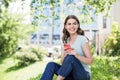 Young beautiful woman using smart phone in a city park. Smiling girl resting outdoor. Student lifestyle concept Royalty Free Stock Photo