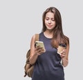 Young beautiful woman using smartphone. Smiling student girl going on a travel holding coffee cup and mobile phone Royalty Free Stock Photo