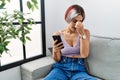 Young beautiful woman using smartphone typing message sitting on the sofa tired rubbing nose and eyes feeling fatigue and headache Royalty Free Stock Photo