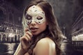 Beautiful brunette with Venetian mask. Young and beautiful woman on Venetian view background. Royalty Free Stock Photo