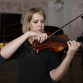 Young beautiful woman violin player looking at camera over instrument on her shoulder holding bow. Royalty Free Stock Photo