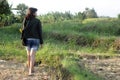 Young beautiful woman walking from behind on field carry, sunflower on bag. Royalty Free Stock Photo