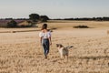 Young beautiful woman walking with her golden retriever dog on a yellow field at sunset. Nature and lifestyle outdoors Royalty Free Stock Photo