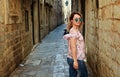 Young beautiful woman walking in old city street, summer Europe vacation, travel, fun, happy, smiling, sunglasses.