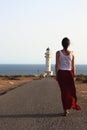 Young beautiful woman walking slowly to Cap de Barberias lighthouse during an amazing summer sunset