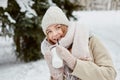 A young beautiful woman walks through a winter park with a cup of hot coffee. Royalty Free Stock Photo