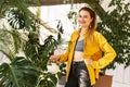 Young beautiful woman watering flowers and plants in her home garden or in a greenhouse, smiling and looking at the camera Royalty Free Stock Photo