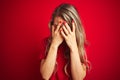 Young beautiful woman wearing basic t-shirt standing over red isolated background with sad expression covering face with hands Royalty Free Stock Photo